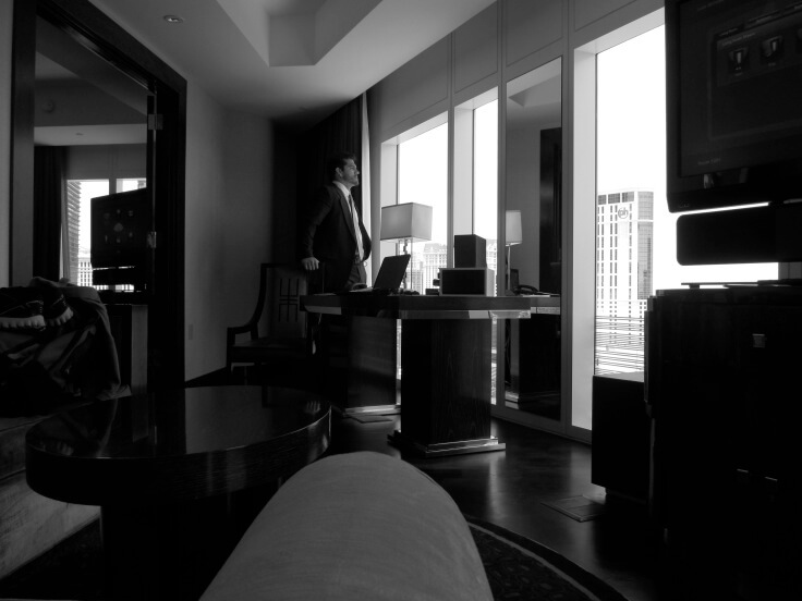 Executive looking out of a window of his hotel room.